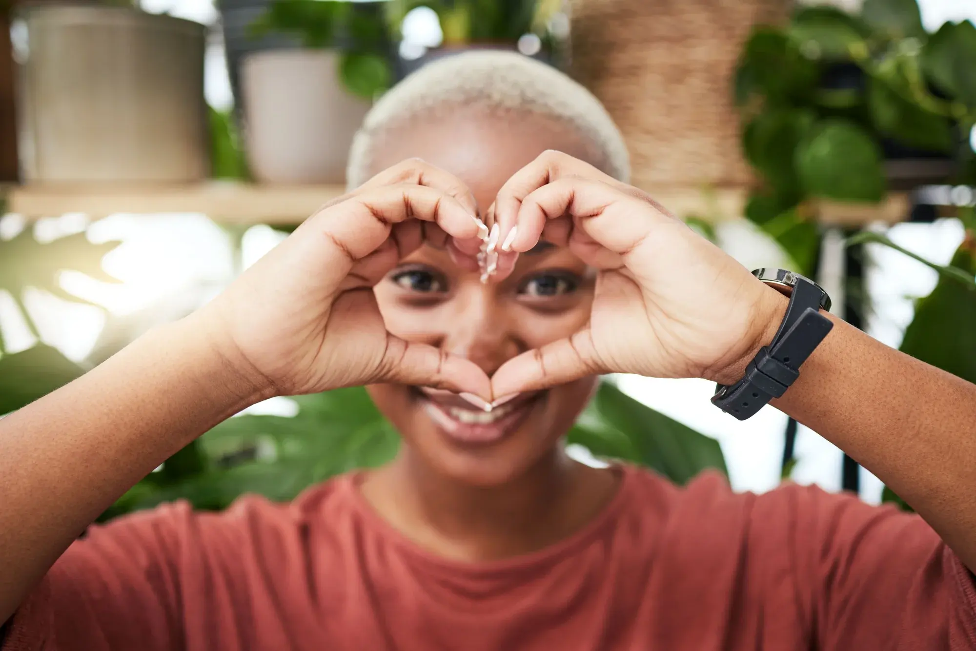 A woman making a heart gesture with her hands, representing community care and love