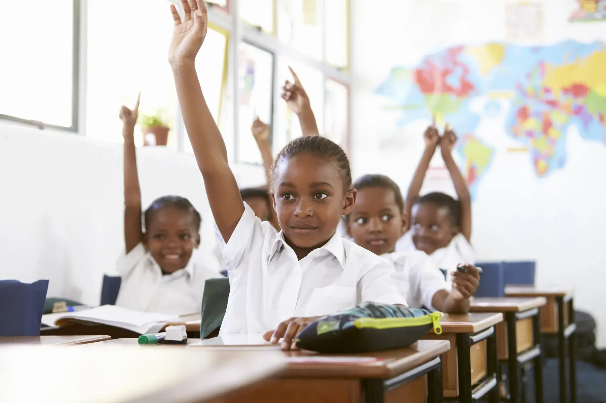Children raising their hands during a lesson in an elementary classroom